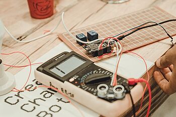 a digital multimeter being used to test an electronic motherboard