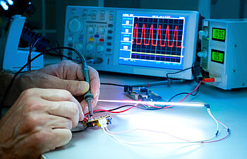 Someone using a digital oscilloscope to test an electronic board